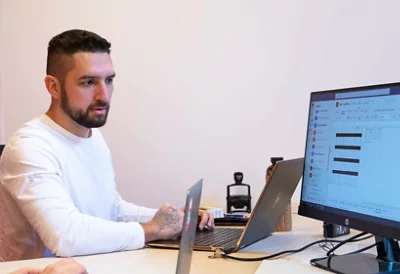 Tattooed hands resting on a laptop.