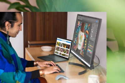 A person multitasks using a Surface Laptop 5 at a desk with an external monitor. 