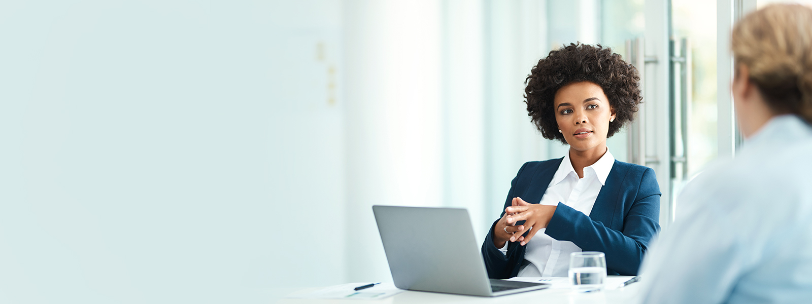 Businesswoman using her laptop while meeting with a client.