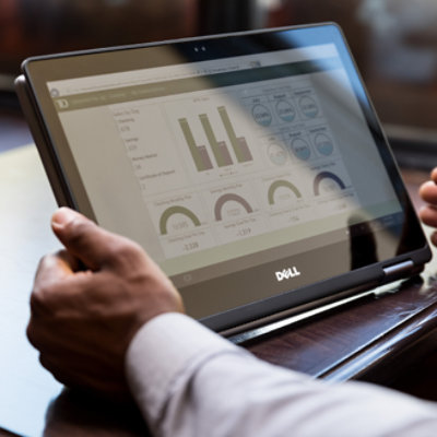 Hands holding a tablet displaying a dashboard with data for TD Bank 