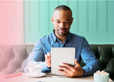 A person sitting and using his tablet with coffee on his table
