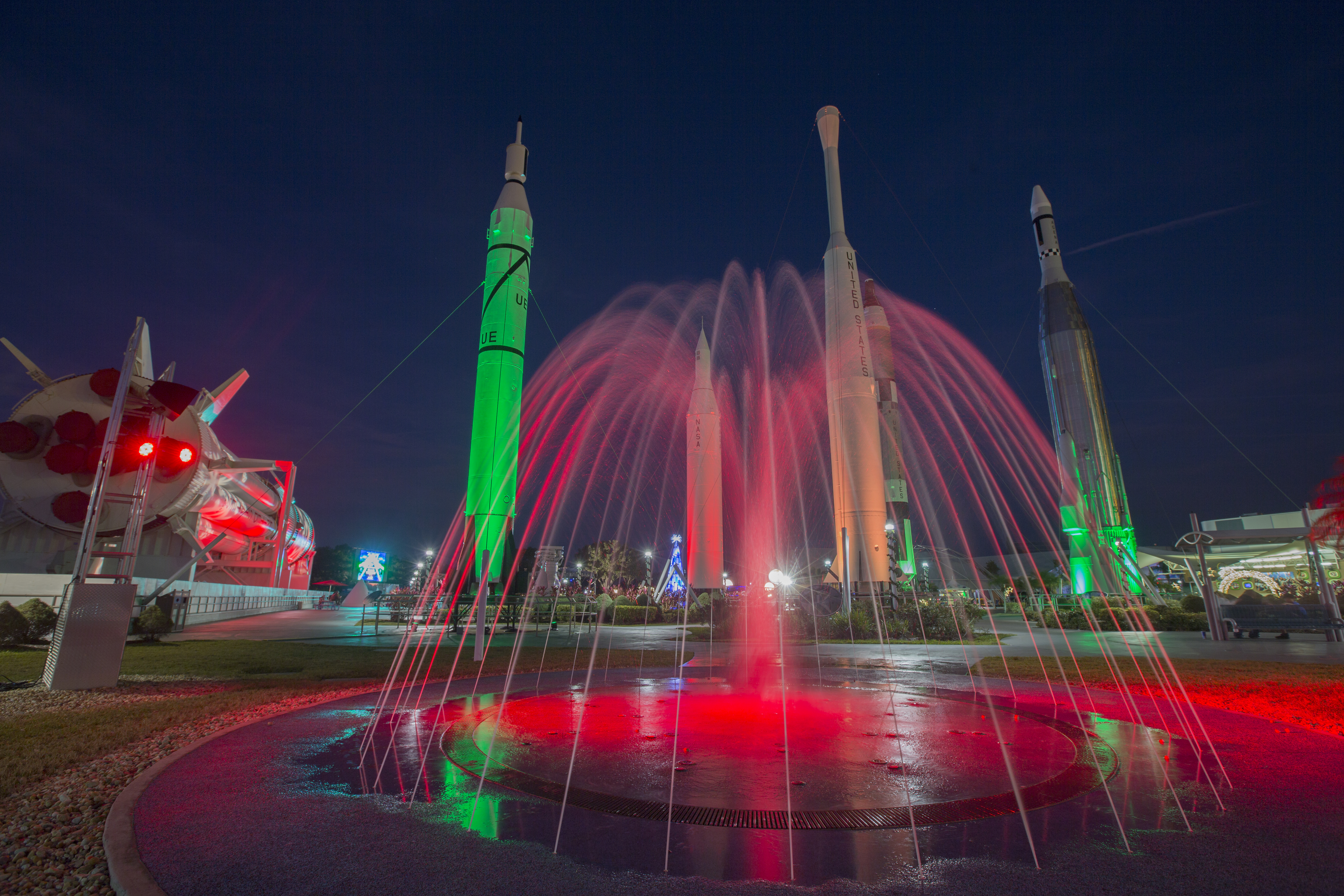 The Rocket Garden and fountain at the Kennedy Space Center Visitor Complex in Florida are lit in green and red for Holidays.