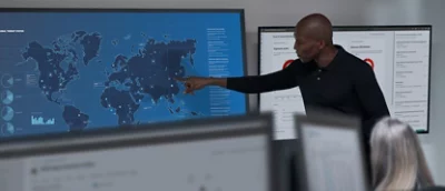 A man is pointing at a map on a screen.