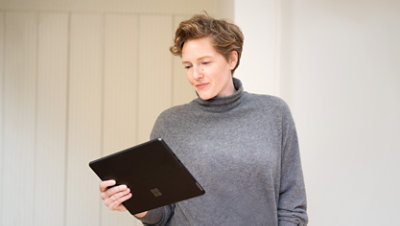 A customer holding a Surface Pro 9 while studying its screen.