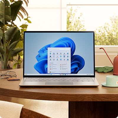 Windows 11-dator med Start-meny och blå blommor