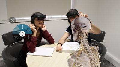 Two people wearing HoloLens 2 devices and viewing a human skeleton.