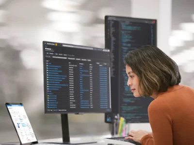 A woman sitting at a desk with two monitors