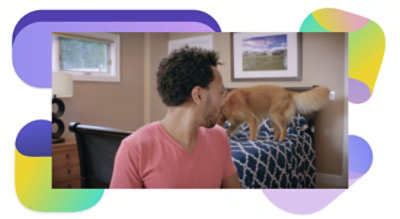 A person sitting at a desk looking back at a dog on their bed.