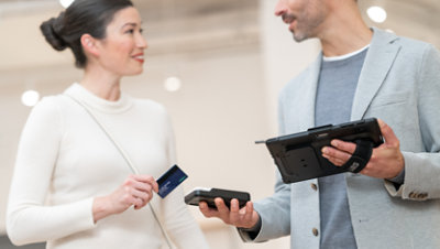 A person uses a Surface Go 4 for Business and various accessories to complete a credit card transaction with a customer.
