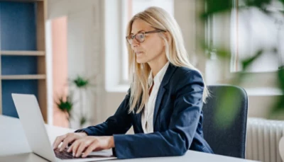 A business woman working on a laptop in an office.