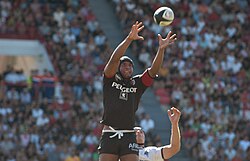 Joueur en l'air, tendant les deux bras en avant pour prendre un ballon en touche.