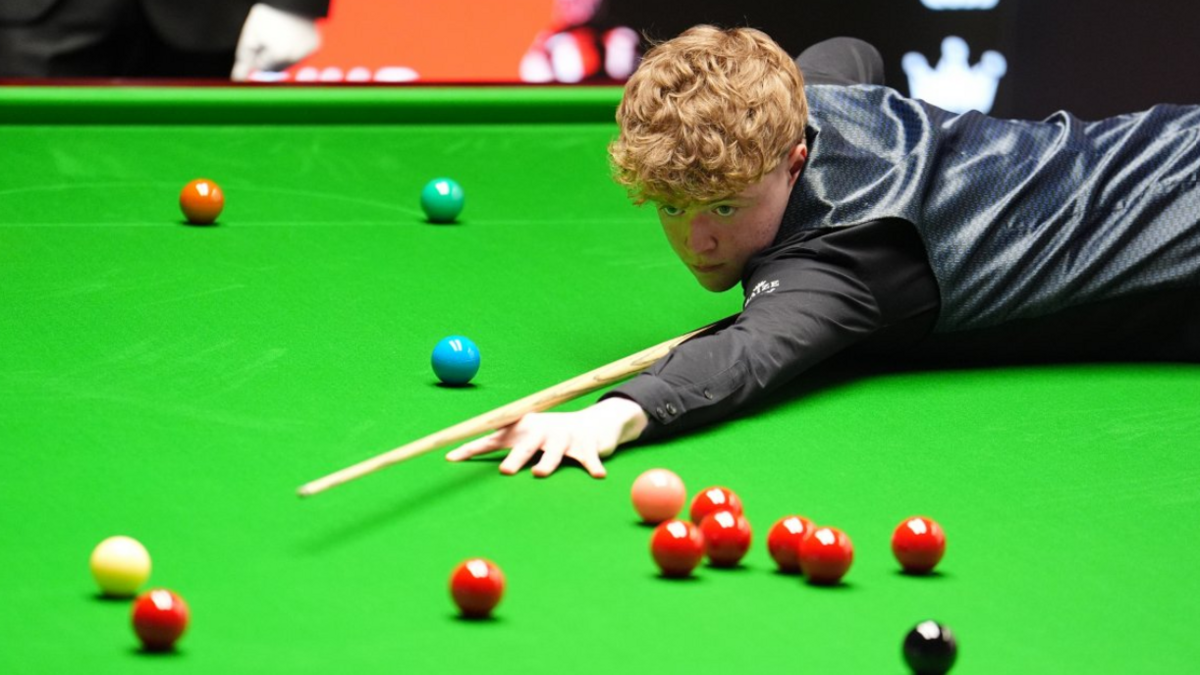 Stan Moody stretches over the snooker table to play a shot