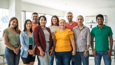 A group of nine people posing together indoors.